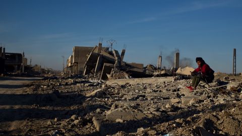 A fighter with the US-backed Syrian Democratic Forces watches the main road through Hajin.