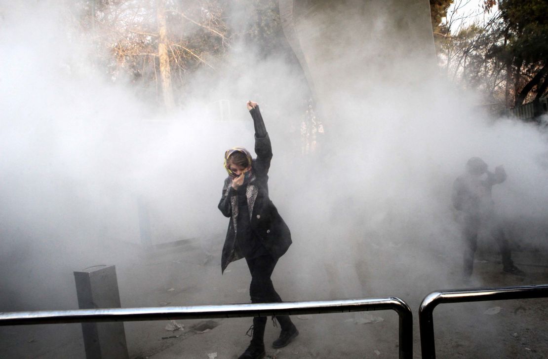 An Iranian woman raises her fist amid the smoke of tear gas at the University of Tehran in December 2017.