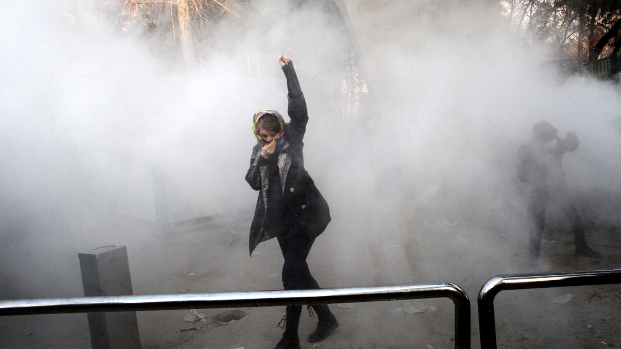An Iranian woman raises her fist amid the smoke of tear gas at the University of Tehran in December 2017.
