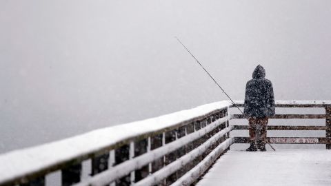 The cityscape is lost in a whiteout as Hershel Odle fishes from a pier in Seattle.