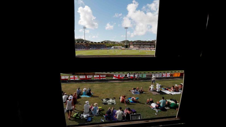 Cricket fans are seen from behind a scoreboard in St. Lucia's National Cricket Stadium on Saturday, February 9.