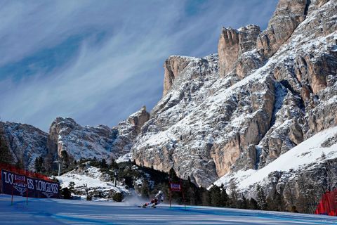 A female skier competes against the domineering backdrop of Cortina's rocky mountains.