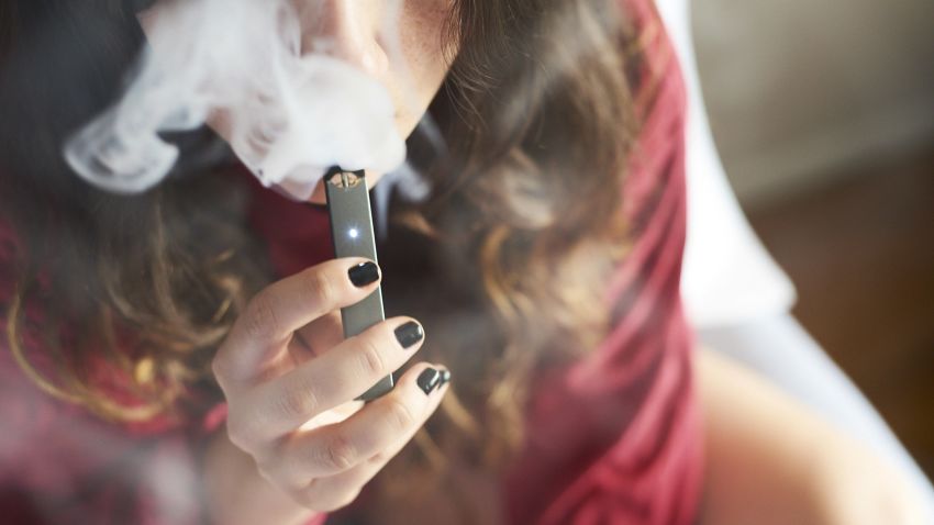 A person smokes a Juul Labs Inc. e-cigarette in this arranged photograph taken in the Brooklyn Borough of New York, U.S., on Sunday July 8, 2018. Juul Labs, the maker of the popular e-cigarette brand that has recently come under fire from health officials over its popularity with young adults, plans to introduce a line of lower-nicotine pods. The company will begin to sell pods with a 3-percent nicotine concentration in its mint and Virginia tobacco flavors later this year, according to a statement Thursday. Photographer: Gabby Jones/Bloomberg via Getty Images