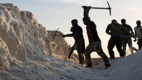 Young men chip away at a hardened mount of salt on Diouf's land in Fatick.