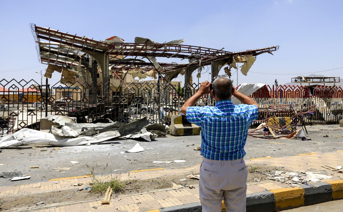 A Yemeni man takes a picture of a destroyed petrol station that was hit by an airstrike in Yemen's capital Sanaa on May 27, 2018.