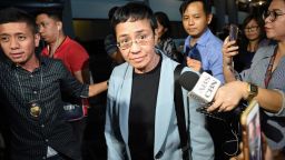 Philippine journalist Maria Ressa is surrounded by the press as she is escorted by a National Bureau Investigation (NBI) agent (L) at the NBI headquarters after her arrest in Manila on February 13, 2019.