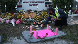 PARKLAND, FLORIDA - FEBRUARY 14: Wendy Behrend, a school crossing guard who was on duty one year ago when a shooter opened fire in Marjory Stoneman Douglas High School pays her respects at a memorial setup for those killed on February 14, 2019 in Parkland,  Florida. A year ago on Feb. 14th at Marjory Stoneman Douglas High School 14 students and three staff members were killed during the mass shooting. (Photo by Joe Raedle/Getty Images)