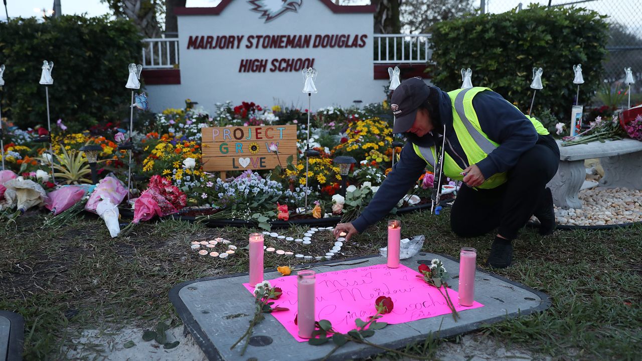 PARKLAND, FLORIDA - FEBRUARY 14: Wendy Behrend, a school crossing guard who was on duty one year ago when a shooter opened fire in Marjory Stoneman Douglas High School pays her respects at a memorial setup for those killed on February 14, 2019 in Parkland,  Florida. 
