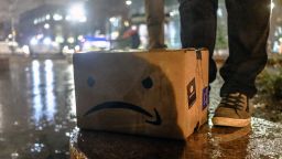 A cardboard box featuring an altered version of the Amazon.com Inc. logo sits on the ground during a protest against the planned Amazon office hub in the Long Island City neighborhood in the Queens borough of New York, U.S., on Monday, Nov. 26, 2018. Despite the influx of investment and jobs, some economists and policy makers have warned that Amazon's giant project will raise housing costs, displacing residents, and increase already snarled traffic. Photographer: Christopher Lee/Bloomberg via Getty Images