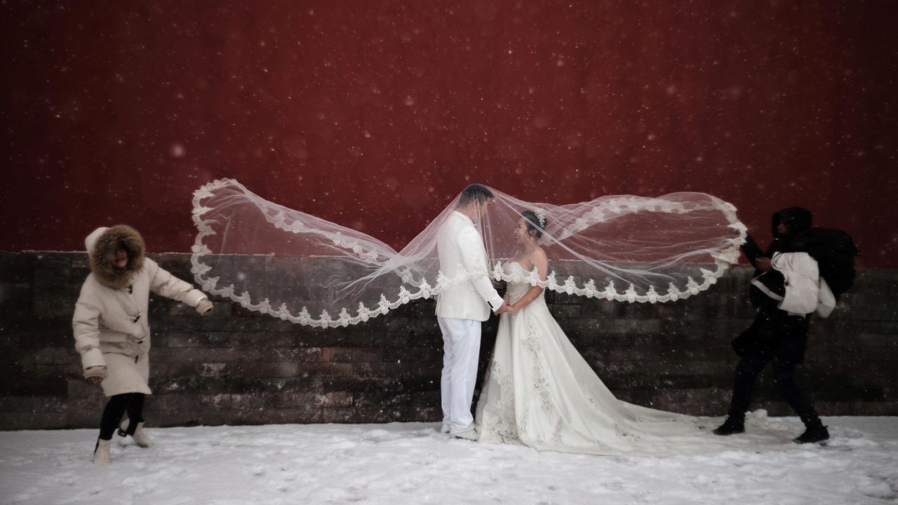 A couple poses for a wedding photo amid snowfall at the Imperial Ancestral Temple in Beijing on Tuesday, February 12.