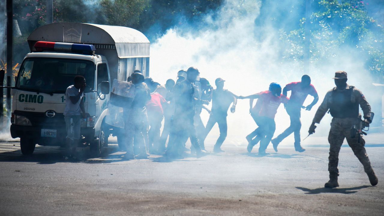 Haitian people run from teargas in the centre of Port-au-Prince on the seventh day of protests against Haitian President Jovenel Moise.