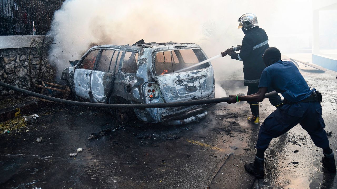 A firefighter extinguishes a car fire at the offices of Television Nationale d'Haiti during protests in Port-au-Prince on Wednesday.