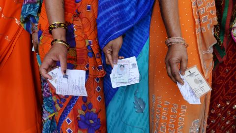 Indian voters pose with their voting slips as they stand in a line to cast their vote outside a polling station at Dabua village on the outskirts of Faridabad on April 10, 2014.