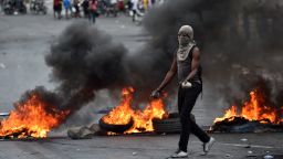 TOPSHOT - A demonstrator walks past next to barricades during clashes with Haitian police, in Port-au-Prince, on February 15, 2019, on the ninth day of protests against Haitian President Jovenel Moise and the misuse of the Petrocaribe fund. - Since February 7, at least seven people have died as Haiti has been plunged into political crisis, with everyday life paralyzed by protests and barricades in the largest towns. (Photo by HECTOR RETAMAL / AFP)        (Photo credit should read HECTOR RETAMAL/AFP/Getty Images)