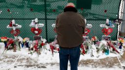 A man prays at a makeshift memorial Sunday, Feb. 17, 2019, in Aurora, Ill., near Henry Pratt Co. manufacturing company where several were killed on Friday. Authorities say an initial background check five years ago failed to flag an out-of-state felony conviction that would have prevented a man from buying the gun he used in the mass shooting in Aurora.