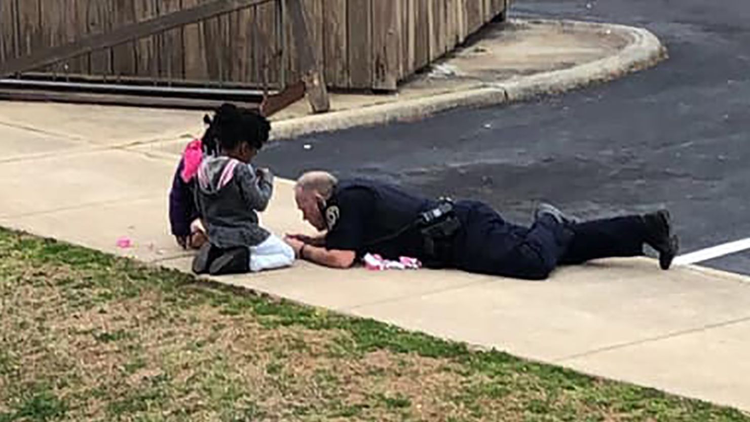 A South Hill officer lays on the ground to play with kids.