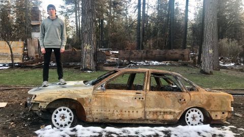 Nate Dailey stands on top of his burned out car in Paradise, California.