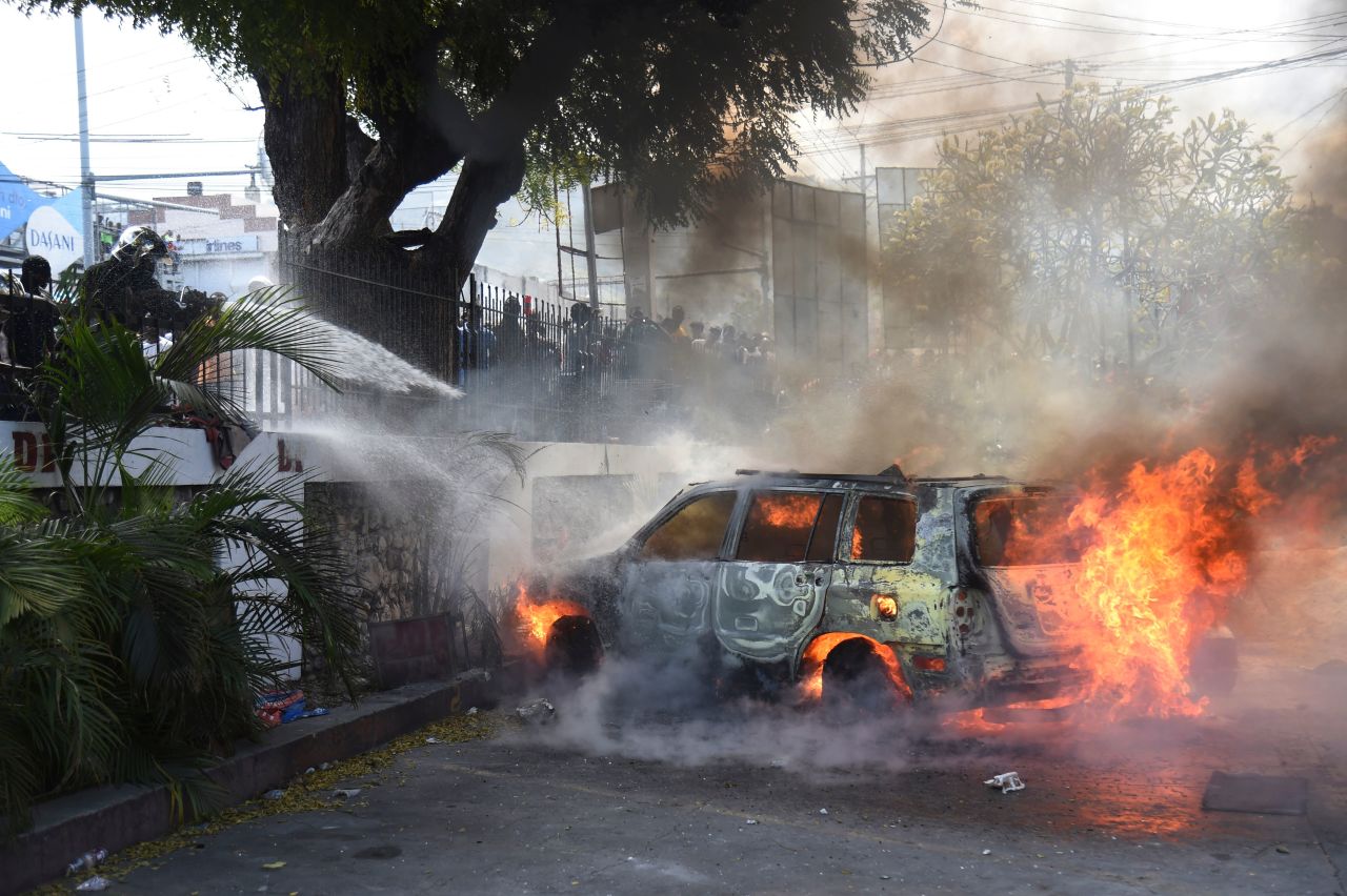 Firefighters extinguish burning cars at the offices of Haiti's state television station on February 13.