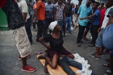 A mother cries while sitting on the body of her dead son who was shot during clashes in Port-au-Prince on February 9.
