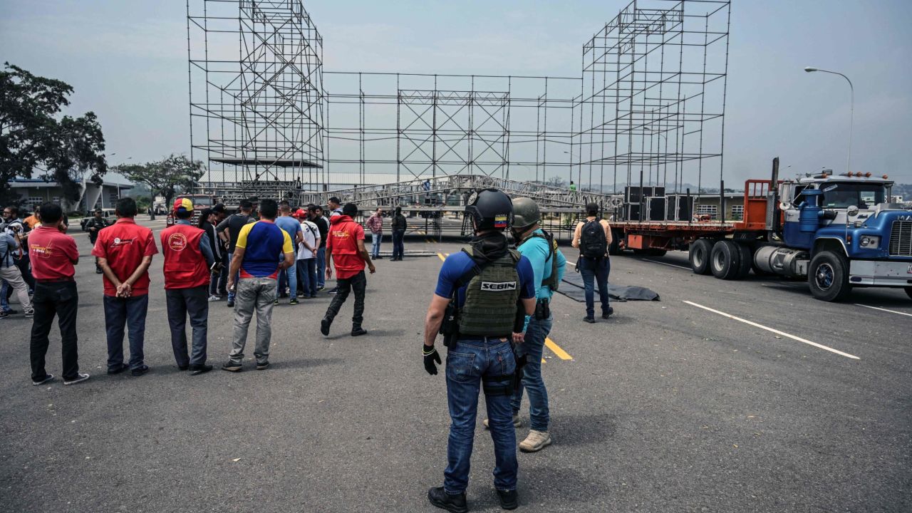 Workers prepare for a rival concert on the Venezuelan side of the bridge as a member of the country's intelligence service looks on.