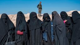 A fighter with the US-backed Syrian Democratic Forces (SDF) keeps watch near veiled women standing on a field after they fled from the Baghouz area in the eastern Syrian province of Deir Ezzor on February 12, 2019 during an operation to expel hundreds of Islamic State group (IS) jihadists from the region. Syrian fighters backed by artillery fire from a US-led coalition battled a fierce jihadist counteroffensive as they pushed to retake a last morsel of territory from the Islamic State group in an assault lasting days. More than four years after the extremists declared a "caliphate" across large parts of Syria and neighbouring Iraq, several offensives have whittled that down to a tiny scrap of land in eastern Syria.