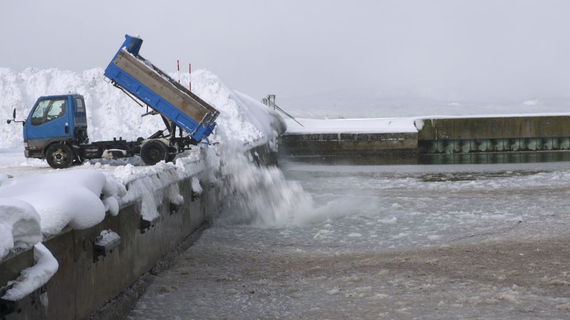 Trucks haul excess snow to an Aomori port, where it's dumped into the sea. 