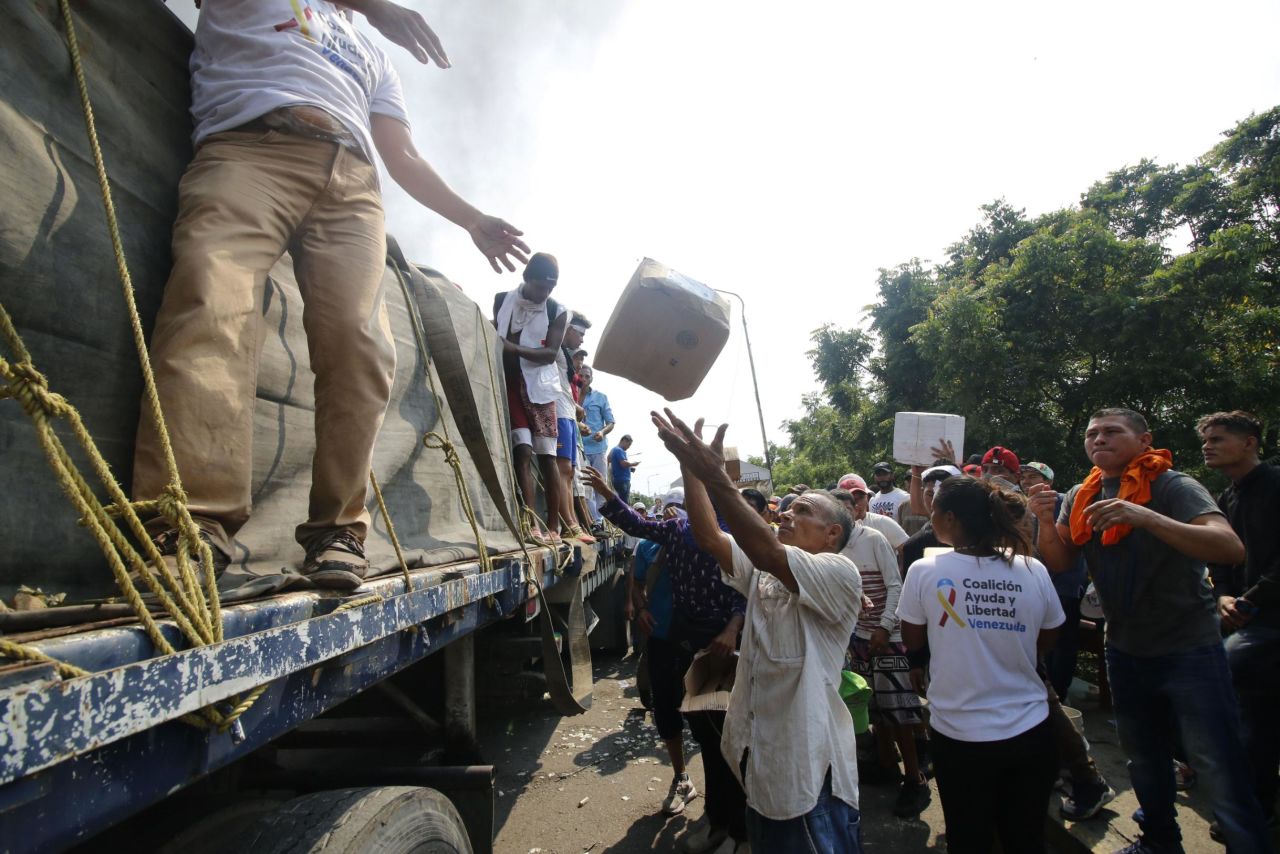 People attempt to salvage packages from a truck loaded with humanitarian aid after it was set ablaze on a bridge between Cucuta, Colombia, and Urena, Venezuela, on February 23.