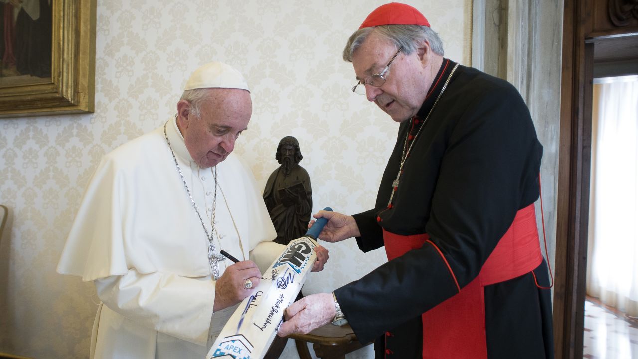 Pope Francis signs a cricket bat he received from Cardinal George Pell, at the Vatican on October 29, 2015.