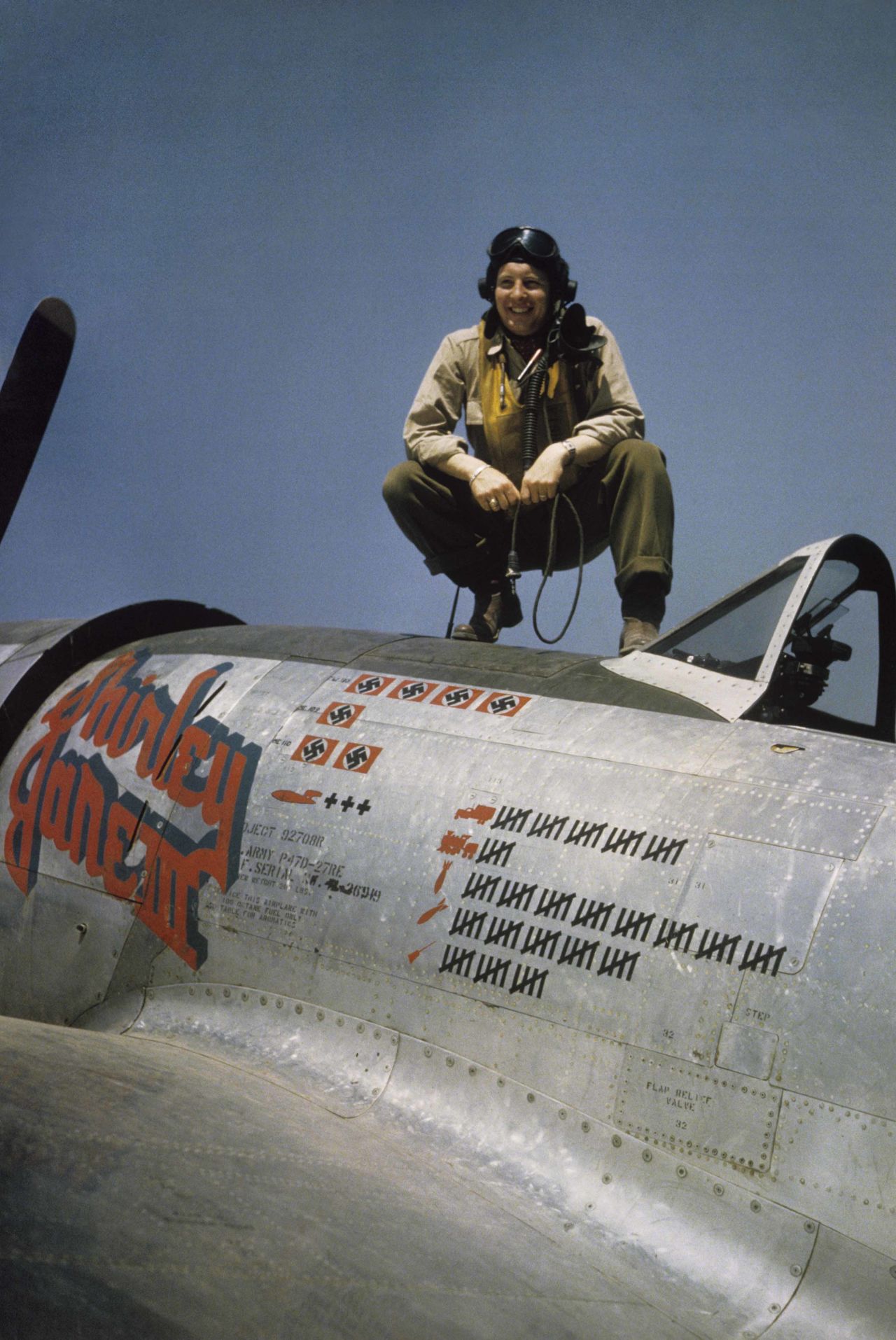 A pilot crouches on top of his plane in France in 1944 © IWM