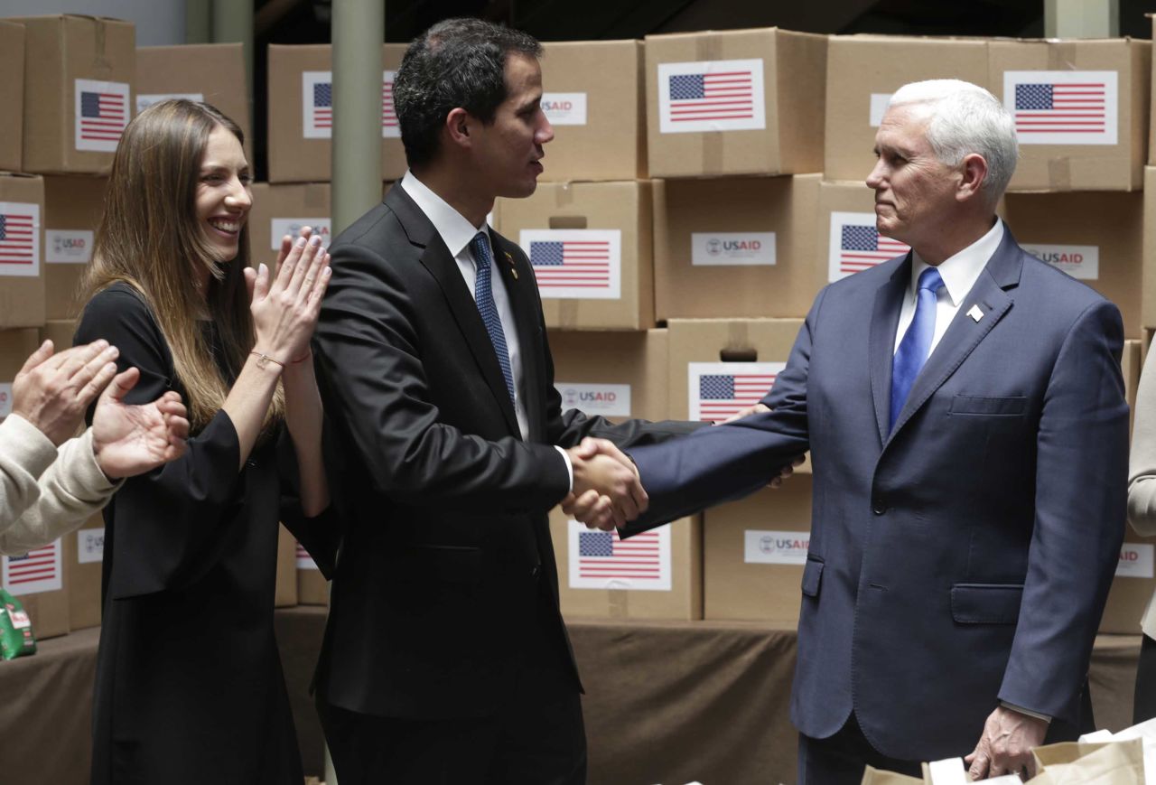 Guaido shakes hands with Pence in Bogota, Colombia, on Monday, February 25. The room was filled with humanitarian aid destined for Venezuela. Guaido's wife, Fabiana Rosales, is pictured at left.