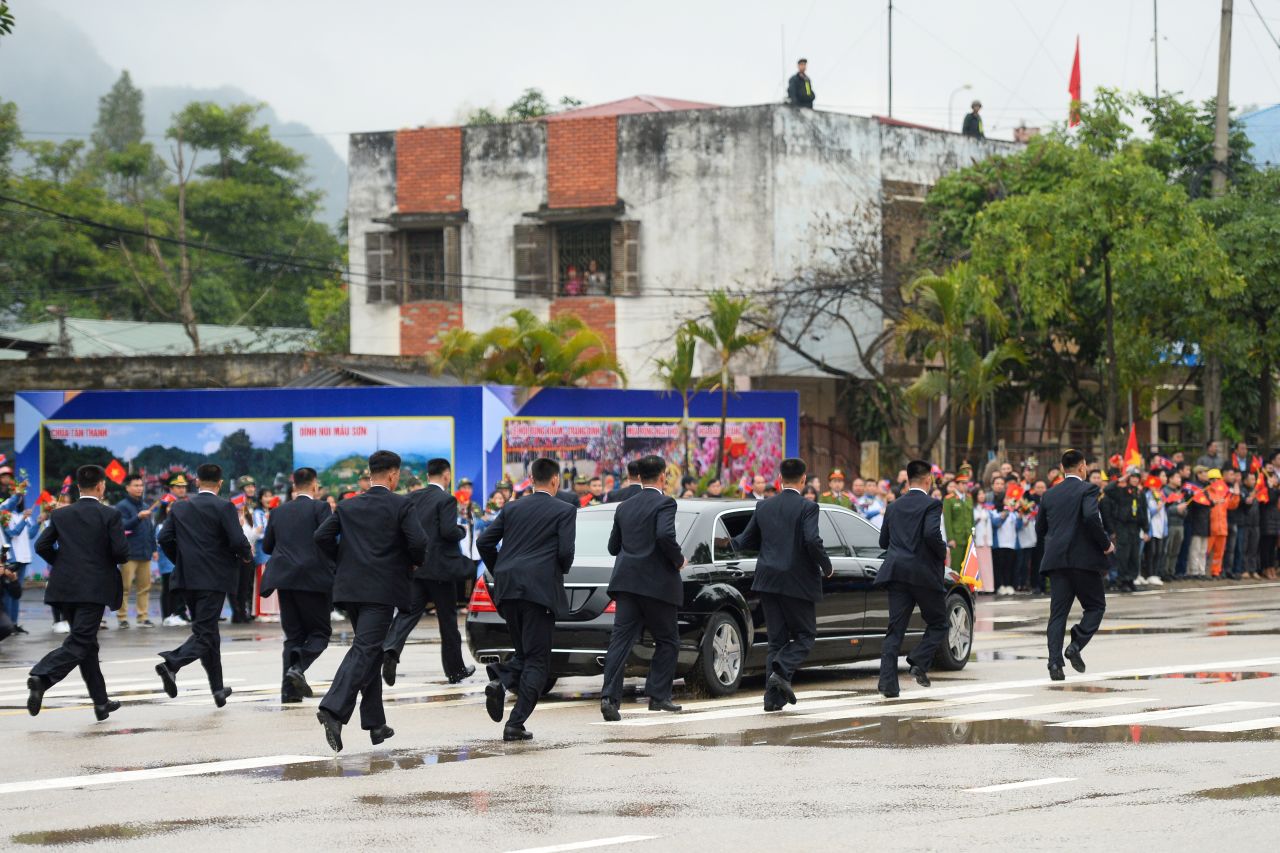 Kim's bodyguards run alongside his car as it leaves the train station.
