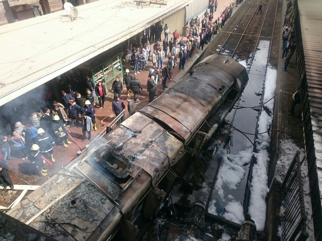 Rescue workers stand next to burned-out wagons sitting on railway tracks Wednesday in Cairo. 