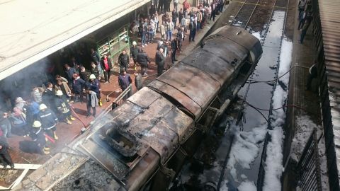 Rescue workers stand next to burned-out wagons sitting on railway tracks Wednesday in Cairo.