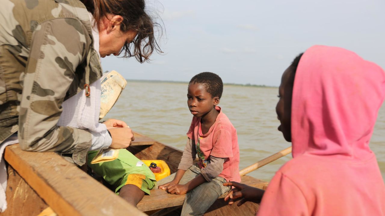 Dominika Kulczyk handing food to young boys working on Lake Volta.