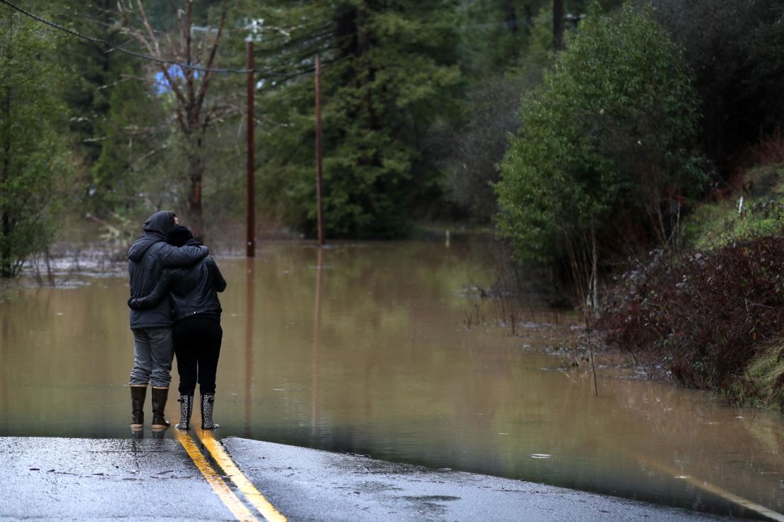 Ari Herman, left, and Lea Herman eye a flooded section of a highway Wednesday in Guerneville.