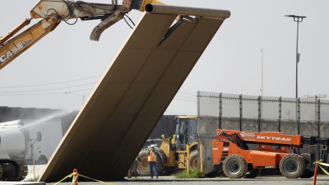 A border wall prototype falls during demolition at the border on Wednesday.