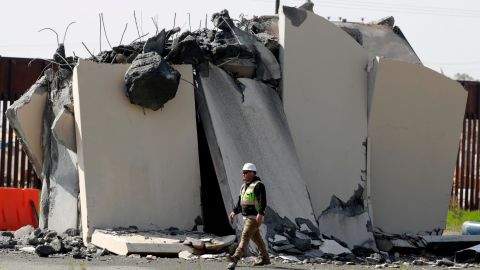 A worker passes a partially demolished border wall prototype on Wednesday.