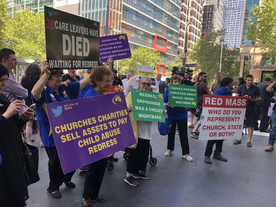 Protesters hold signs outside the County Court in Melbourne, Victoria on February 27, 2019 during a hearing for convicted pedophile Cardinal George Pell. 