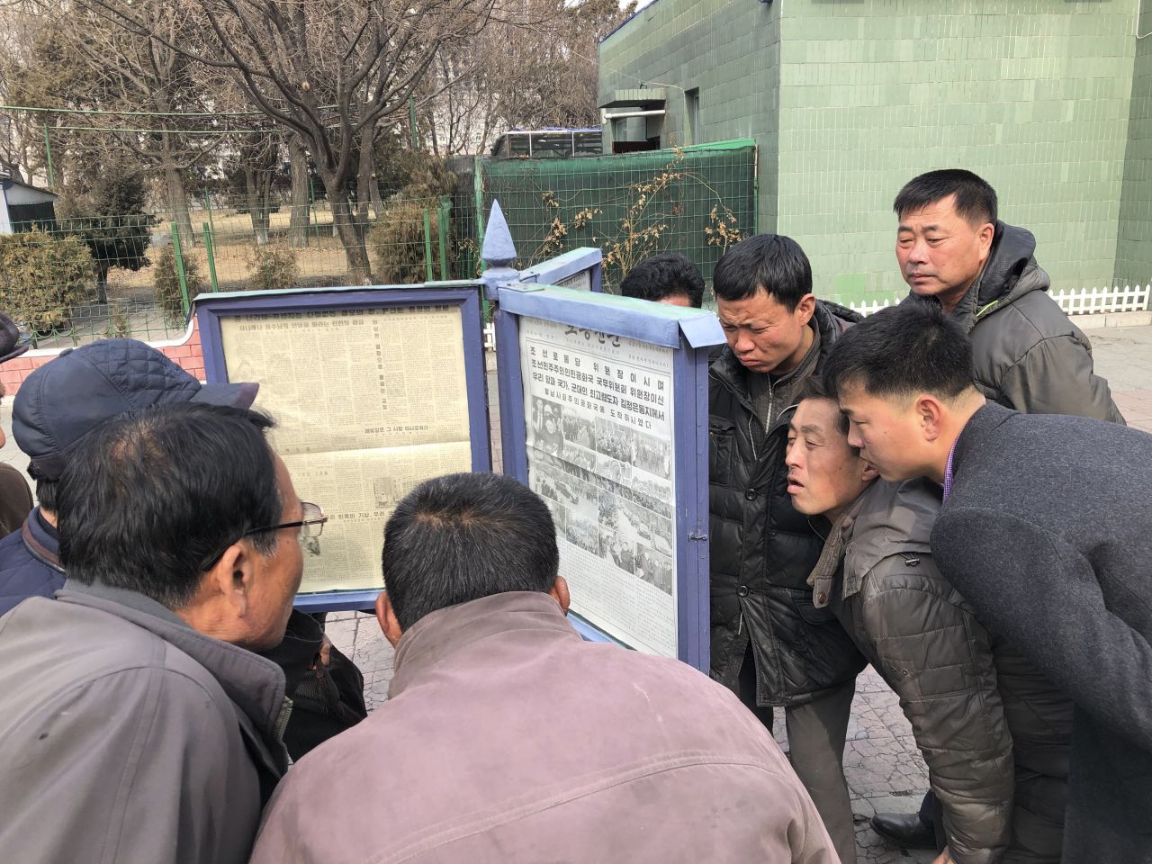 Men in Pyongyang, North Korea, gather around public newspaper posts to read about Kim's visit.