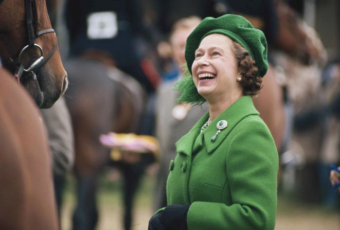 Circa 1980: Dressed in vibrant green, Queen Elizabeth admires the horses at the Royal Windsor Horse Show.