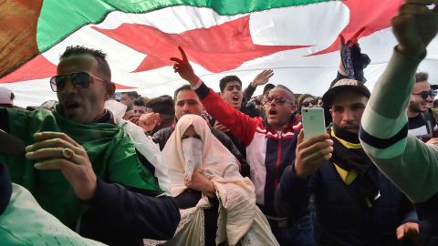 Algerians chant slogans under a national flag Friday in the capital.