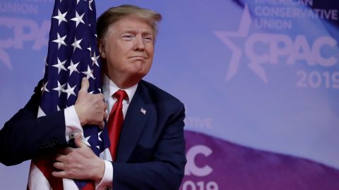 President Donald Trump hugs American flag at the CPAC annual meeting, March 2, 2019. 