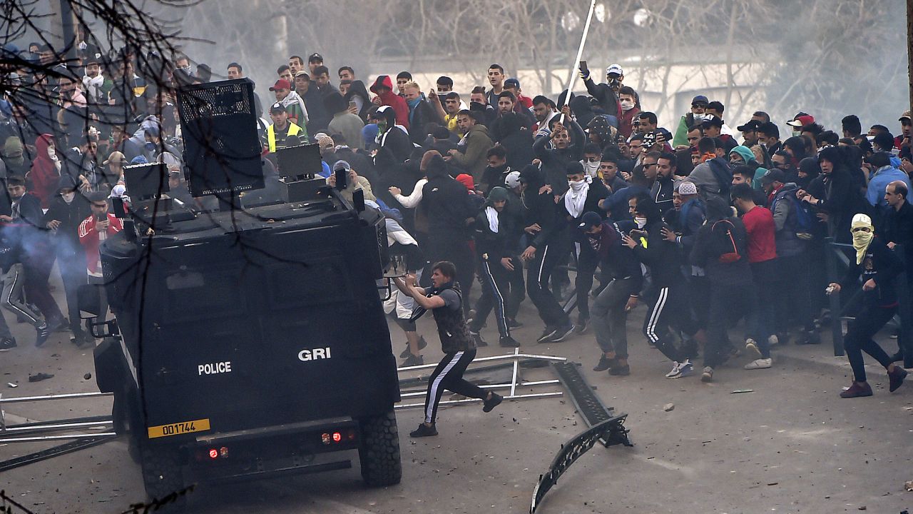 Protestors attempt to overturn a police van in Algiers on Friday.