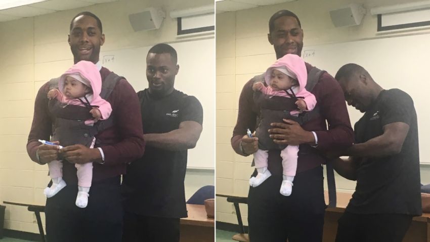 Wayne Hayer helps fasten his daughter Assata in a harness worn by his professor, Nathan Alexander. The professor offered to carry the baby during class so Hayer could take notes.