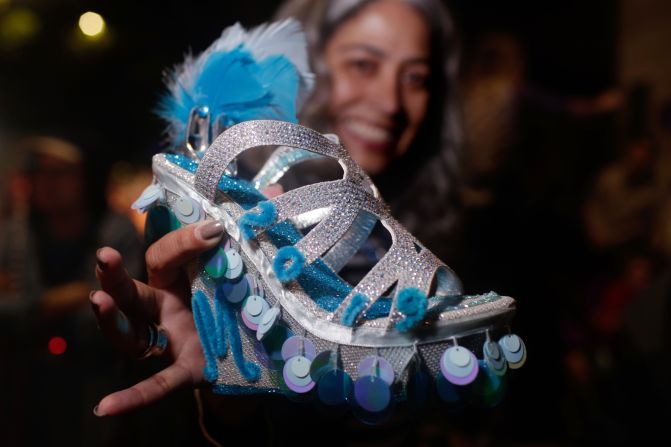 Susan Reyes holds a shoe she was thrown during the parade from her friend Maria Alvarez, who is a member of the Krewe of Muses. The shoe is the Mardi Gras trademark of Muses, and members create detailed artwork from shoes to use as throws in the parade. Often krewe members will alert family and friends about what number their float is and what level they will be on, to assure delivery of a coveted shoe.