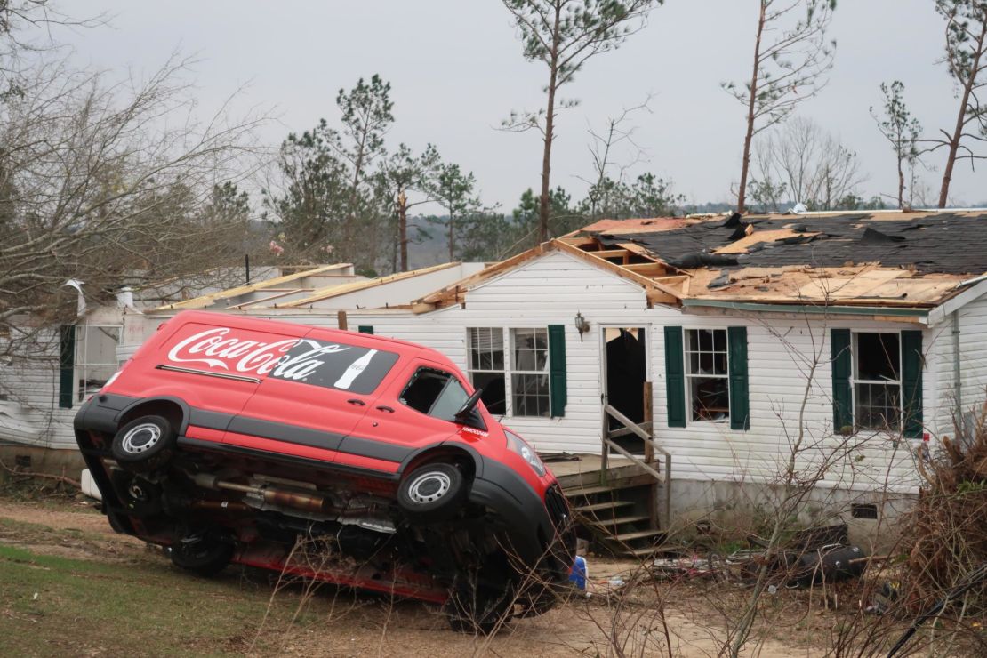 A van is upended in front of a damaged home in Lee County, Alabama, on Monday.