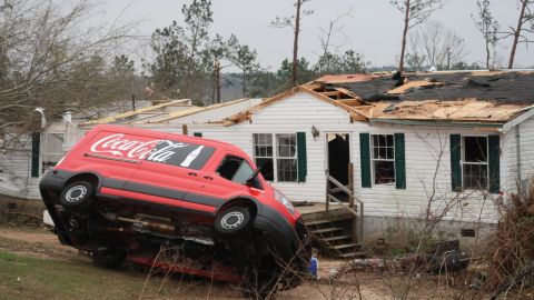 A van is upended in front of a damaged home in Lee County, Alabama, on Monday.