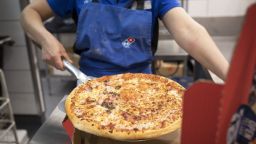 An employee places a cooked pizza into a delivery box inside a Domino's Pizza Group Plc store in Hanwell, London, U.K., on Monday, Feb. 27, 2017. Domino's Pizza said given continued strong new store performance and positive outlook both for its market and brand, it is increasing its long term target for the U.K. to 1,600 stores. Photographer: Jason Alden/Bloomberg via Getty Images