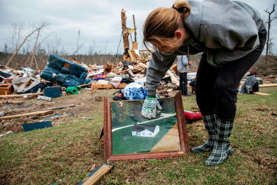 Ashley Griggs wipes away dirt from a photo that shows what a Beauregard home looked like before it was destroyed.