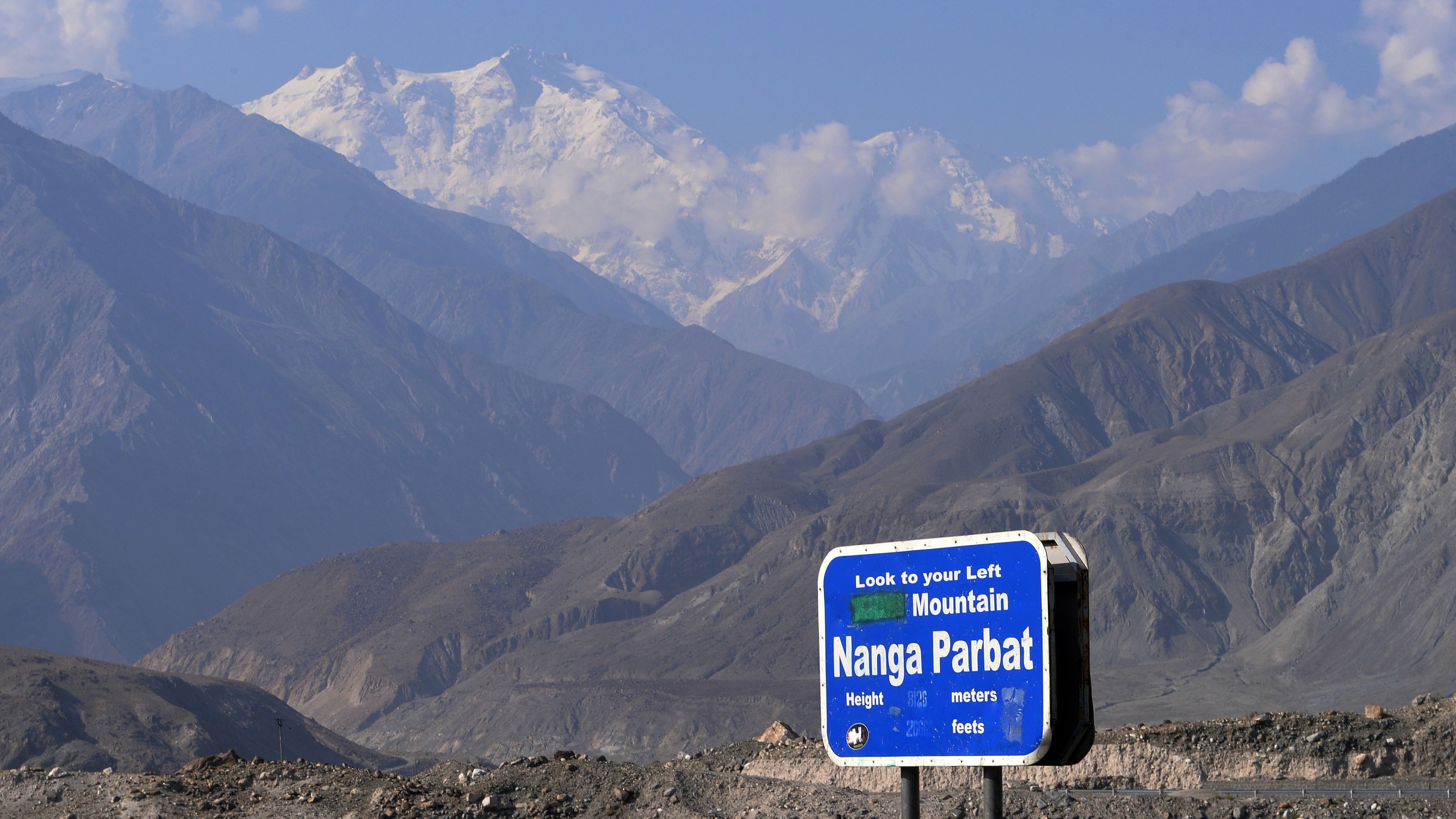 In this photograph taken on August 7, 2014 a sign points towards a view of Nanga Parbat (background), the killer mountain on Karakoram Highway in Pakistan's nothern area of Gilgit.